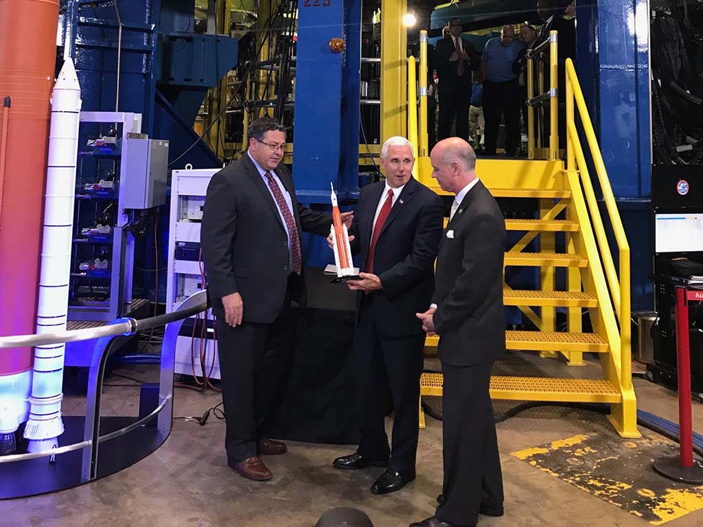 A photo of Vice President Pence holding a scale model of the SLS while touring Marshall Space Flight Center
